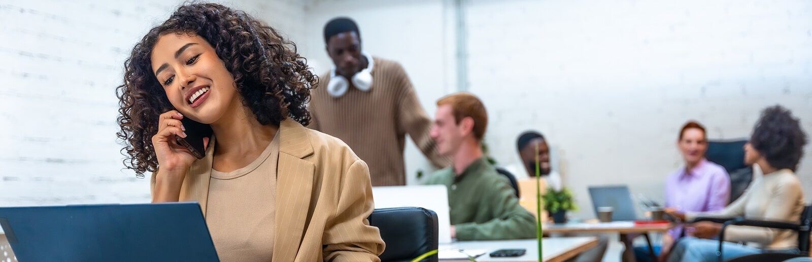 a woman talking on the phone in the office and people gathered behind her