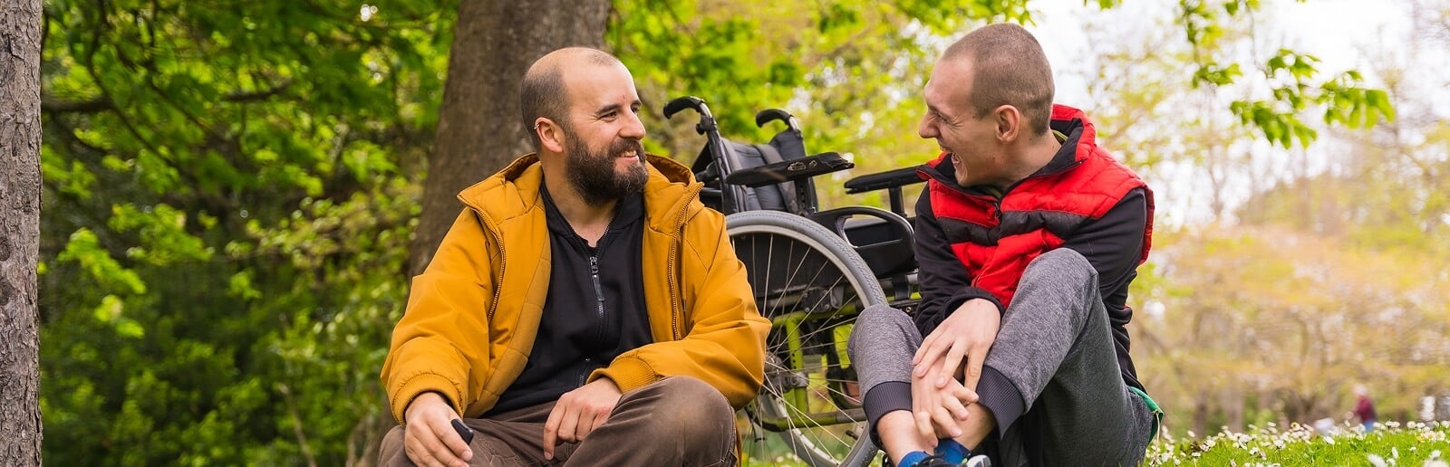 a man in a wheelchair and a man next to him talking and laughing together