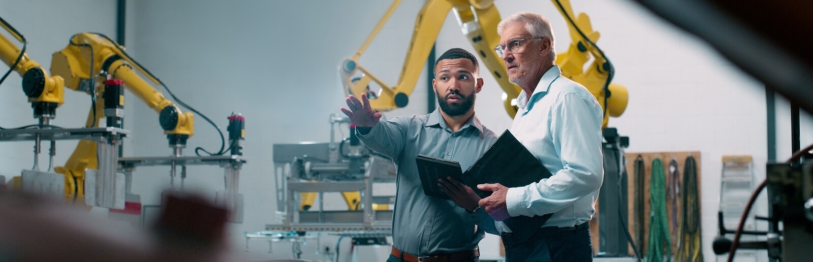 two men talking and working around hi-tech manufacturing equipment