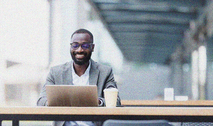 a business man smiling and working on a laptop