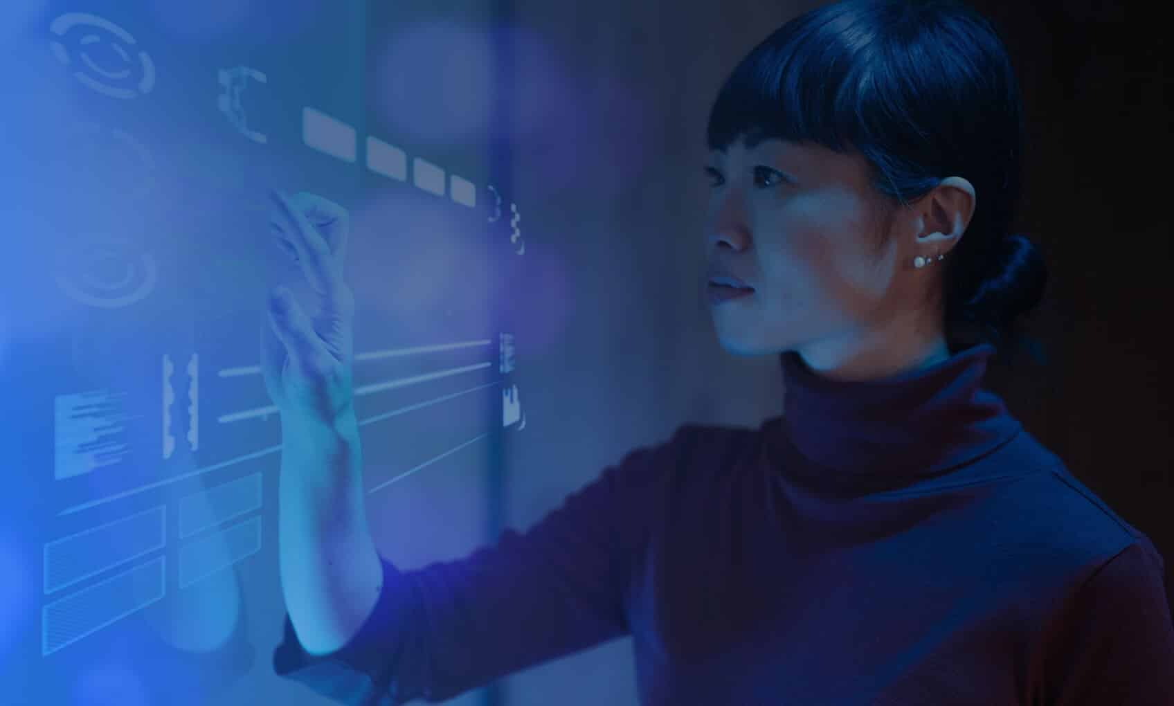 A person explores a glowing digital interface, touching virtual buttons on a transparent screen in a dark room aglow with blue and purple light—demonstrating advanced Email Security Implementation features.