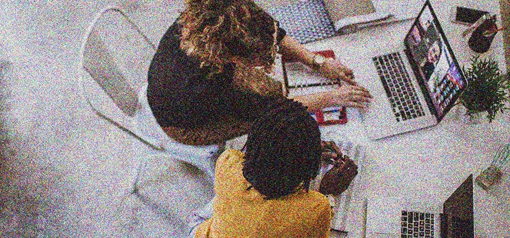 two women working on laptops together