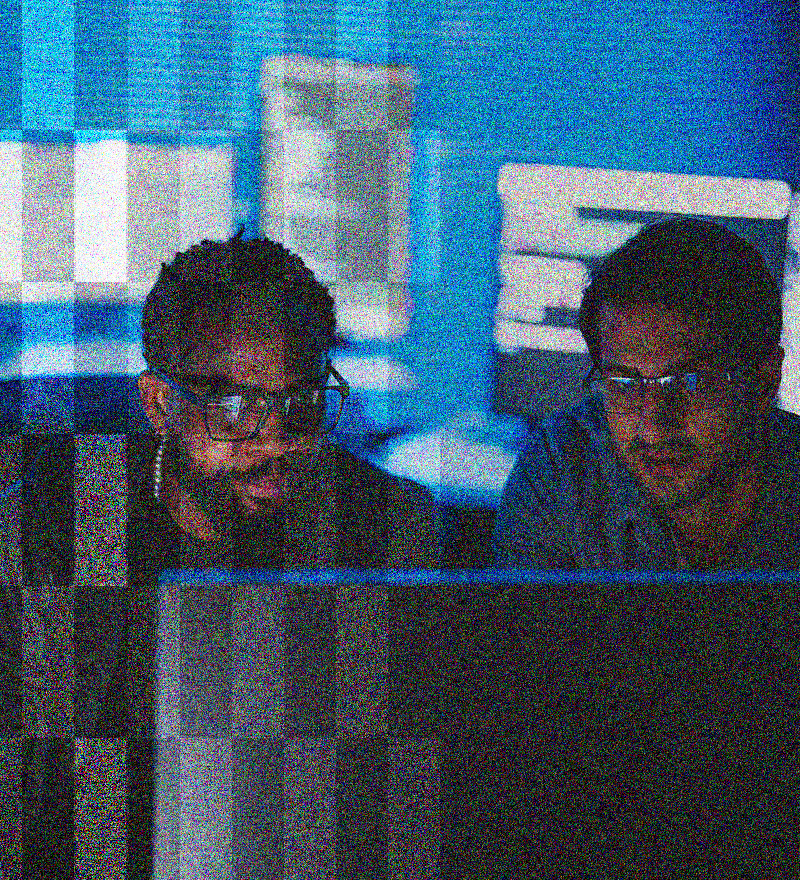 two men wearing glasses and working on a computer together