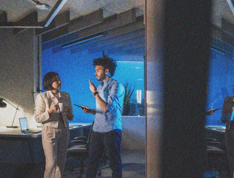 man and woman talking and working on a tablet together
