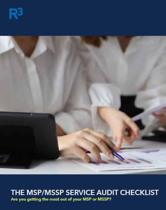 Two people in white shirts review printed charts with graphs and use a pen while working at a desk with a tablet. Text below reads, THE MSP/MSSP SERVICE AUDIT CHECKLIST.
