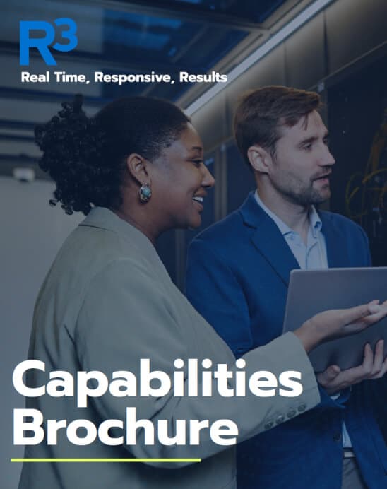 Two professionally dressed people, a woman and a man, stand together in an office hallway discussing something on a tablet. Text reads: Capabilities Brochure. R3 logo and slogan are at the top.